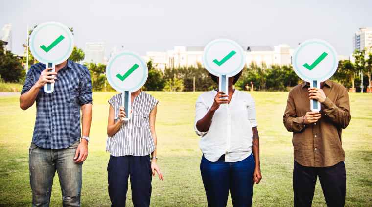 four people holding green check signs standing on the field photography